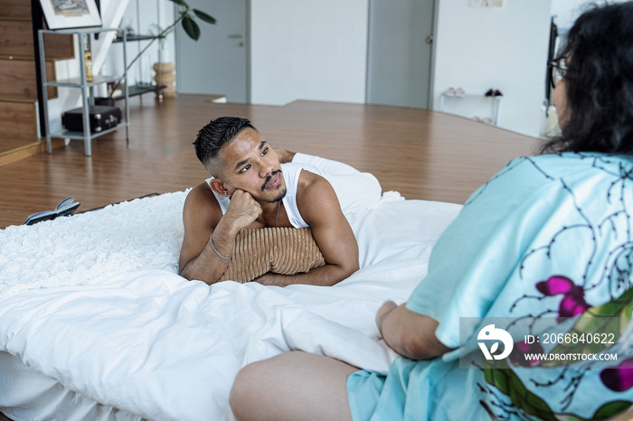 Three friends chatting and laughing together at home in bed