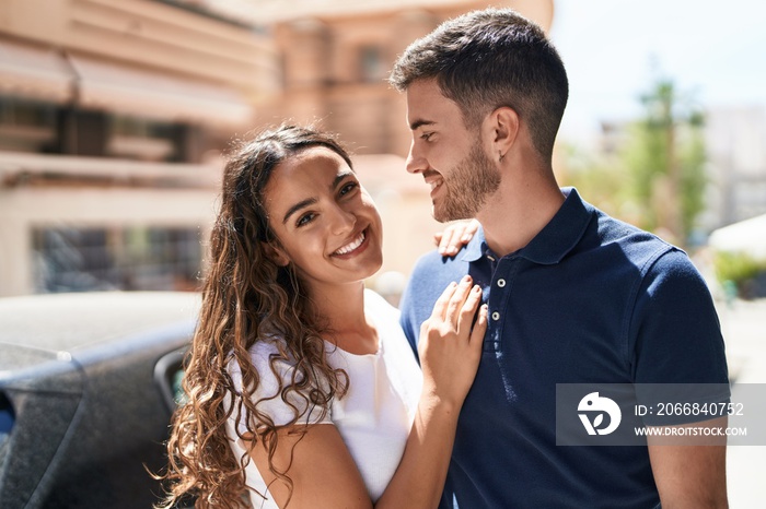 Young hispanic couple smiling confident hugging each other at street