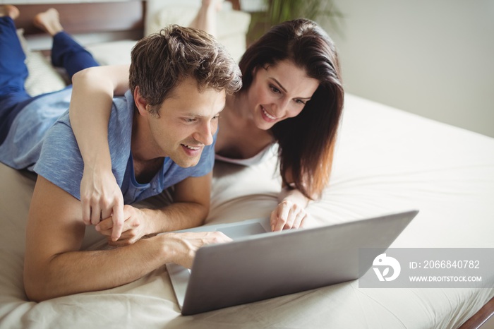 Happy couple using laptop on bed