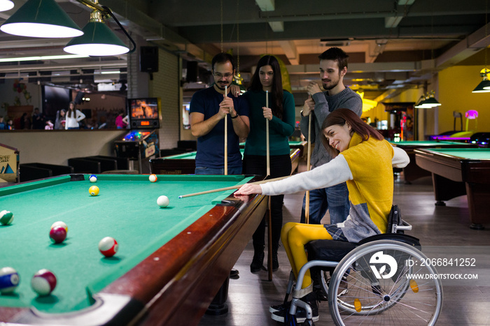 Disabled girl in a wheelchair playing billiards