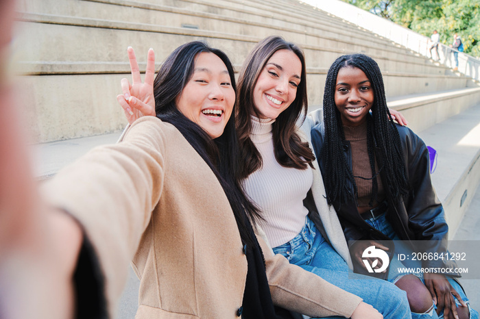 Happy group of multiracial young women taking a selfie portrait smiling at camera. Three diverse girls having fun outdoors. Best friends taking a photo. High quality photo