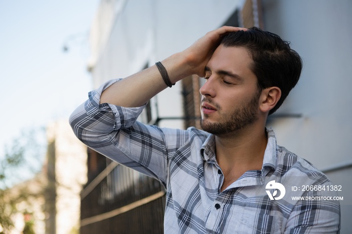 Tensed man sitting by wall