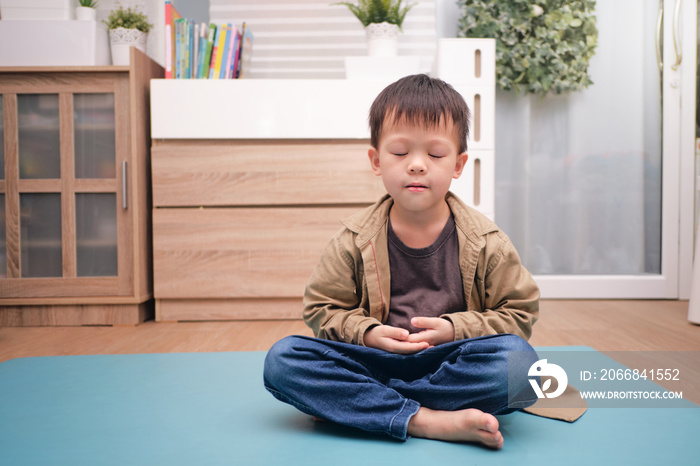 Little Asian kid with eyes closed, barefoot practices yoga & meditating to relieve negative emotions on weekend at home, Beginner meditation, Breathing exercise for kids, Healthy lifestyle concept