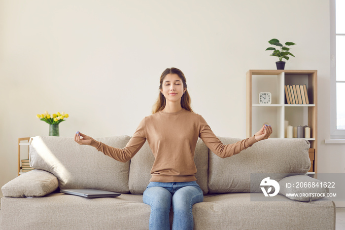 Take break. Portrait of young calm casual woman relaxing and meditating sitting on sofa in living room. Smiling girl with closed eyes relieves stress after working on laptop at home.