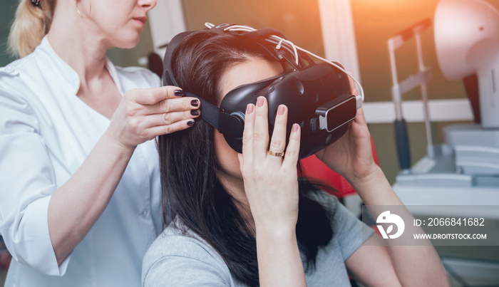 Ophthalmology doctor checks the girl’s vision with the help of virtual reality goggles.