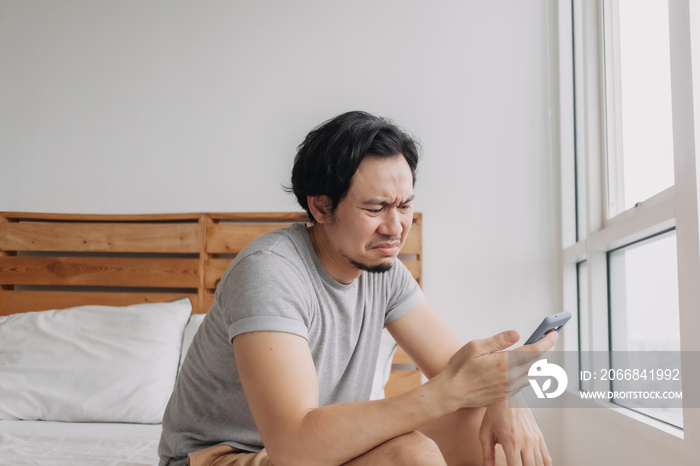 Sad Asian man has bad online chat news and feels disappointed on the smartphone.