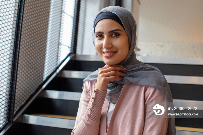 Portrait of smiling woman wearing headscarf sitting on steps