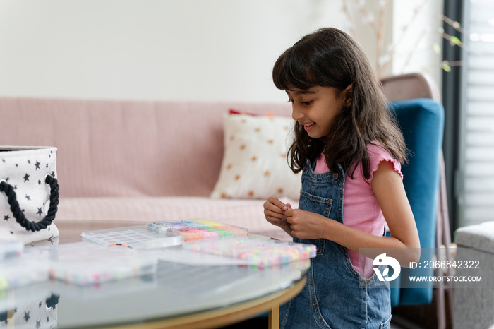 Little girl playing with beads in living room