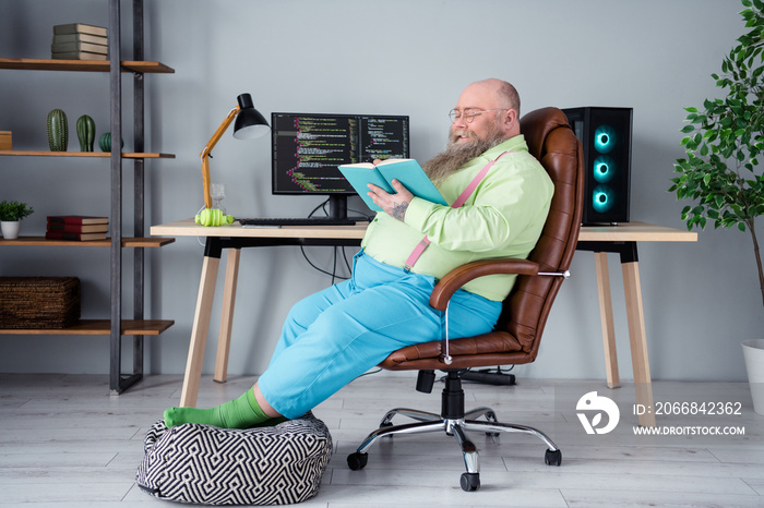 Profile side view portrait of attractive focused smart guy sitting in chair reading interesting book at office indoor work place station