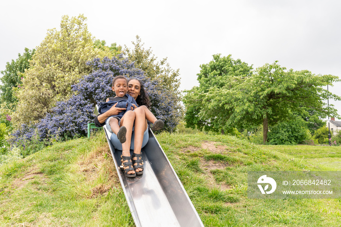 Mother and son having fun on slide at playground