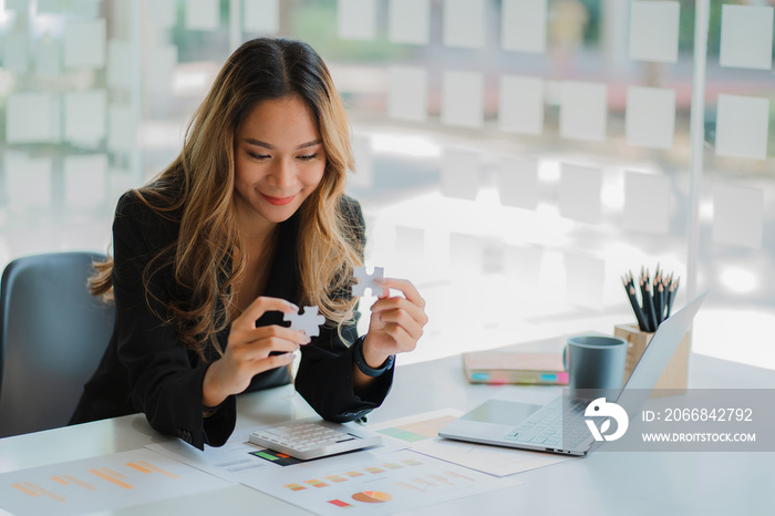 Asian businesswoman playing puzzle symbolic problem solving and working financial accounting work concept.