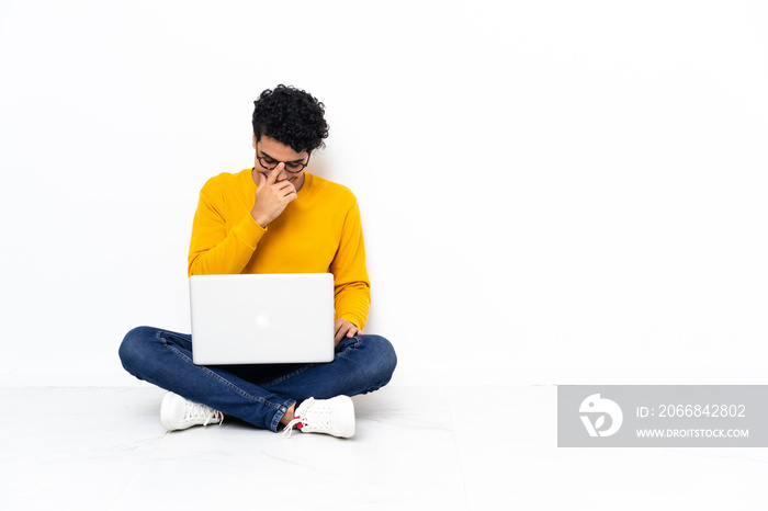 Venezuelan man sitting on the floor with laptop laughing