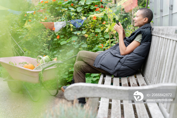 Smiling woman with smart phone in vegetable garden