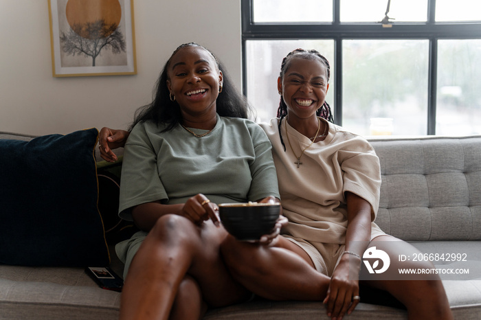 Portrait of lesbian couple sitting on sofa at home