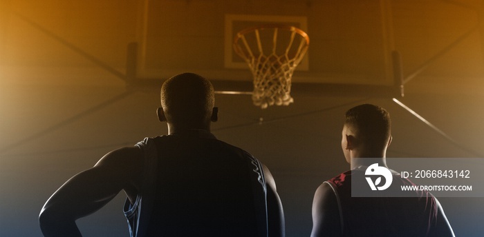 Two basketball player looking the basketball hoop