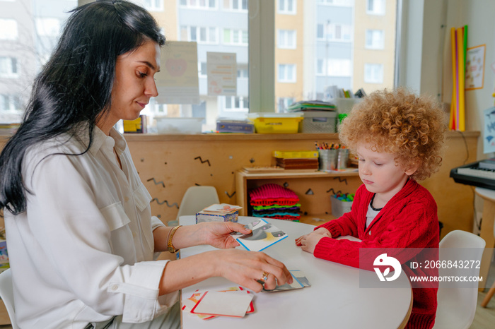 Teacher spreads out puzzle in front of the child