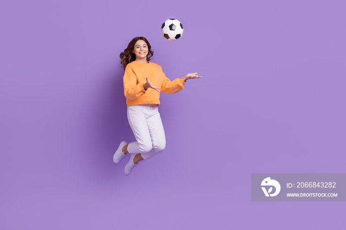 Full length photo of cheerful excited girl jumping arms catch throw football isolated on violet color background