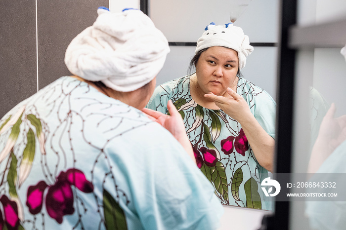 Plus size female examining her skin in the mirror