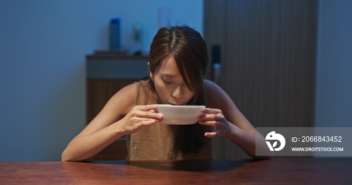 Woman drink of hot soup at home in the evening