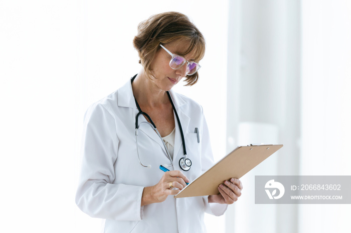 Concentrate female doctor with eyeglasses reviewing medical reports in the office at hospital.