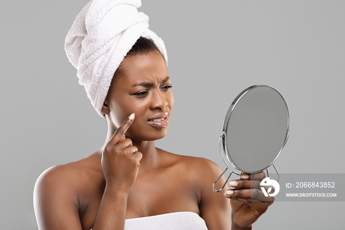 Dissapointed black woman looking into the mirror after bath