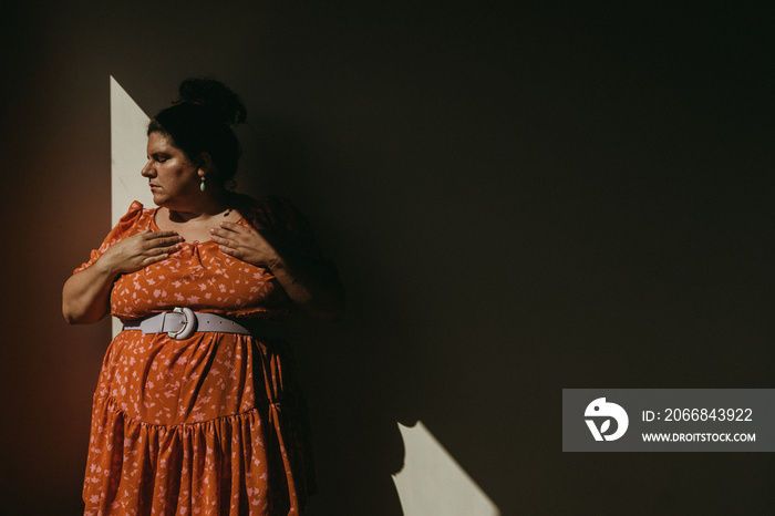 portrait of a plus size woman hands on chest looking down