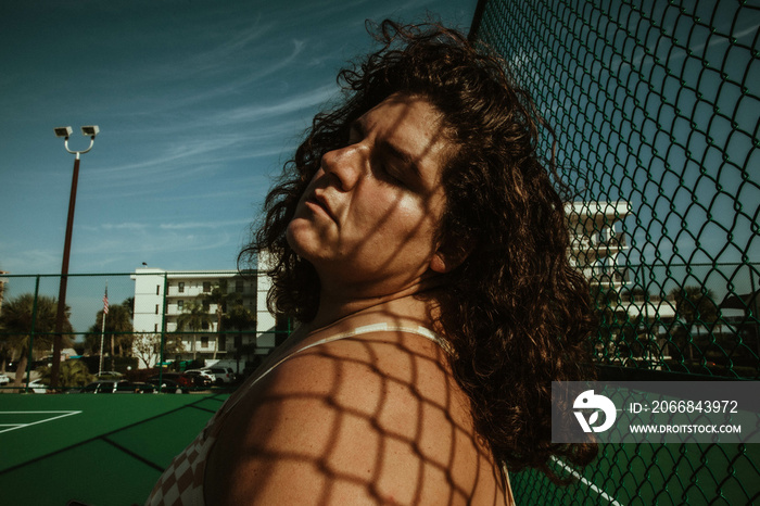 portrait of a plus size woman with chain link shadow on face