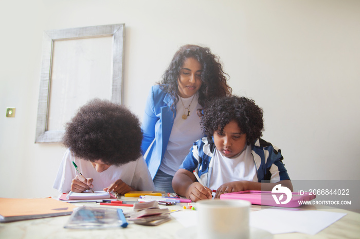 Mid-sized mother helping her children with homework and drinking coffee