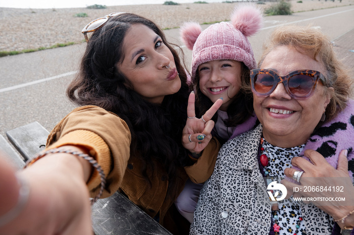 Grandmother, mother and daughter taking selfie on beach