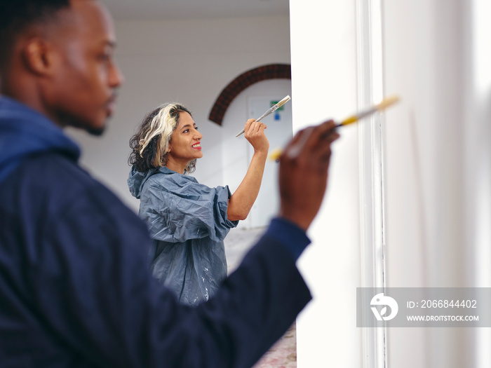 Smiling couple painting house walls