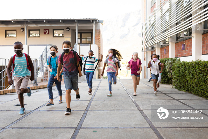 Group of diverse students wearing face masks running at elementary school