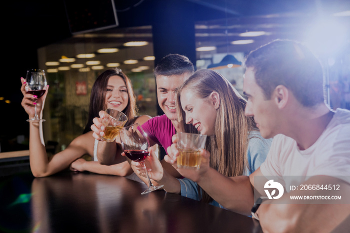 Cheerful friends in the pub. Drinking beer, wine and whisky, talking, having fun.