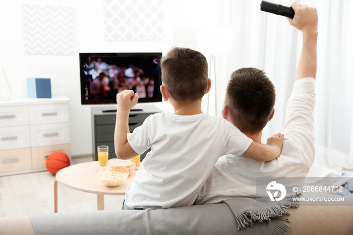 Father and son watching television at home. Leisure and entertainment concept