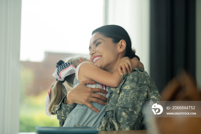 Military woman laughing while hugging her daughter