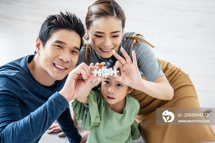 Happy family, Asian little daughter playing jigsaw puzzle with her mother and father for family concept, They assembling Jigsaw Puzzle..