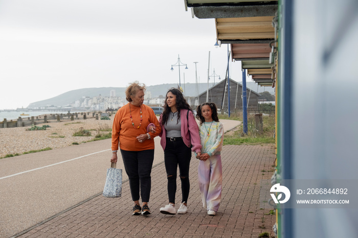 Grandmother, mother and granddaughter walking by beach huts