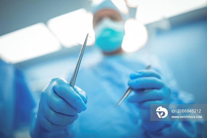 Surgeon holding surgical tools in operation theater