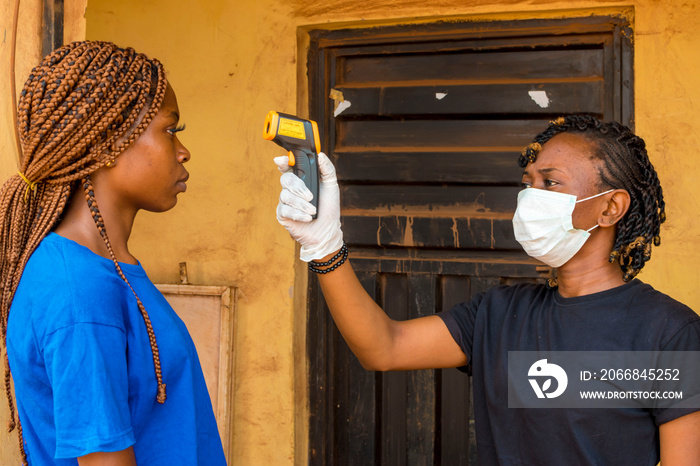 young black lady using a handheld infrared thermometer to test a lady’s temperature