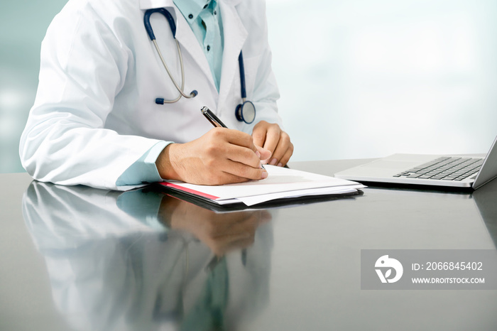 Male doctor sitting at table and writing on a document report in hospital office. Medical healthcare staff and doctor service.