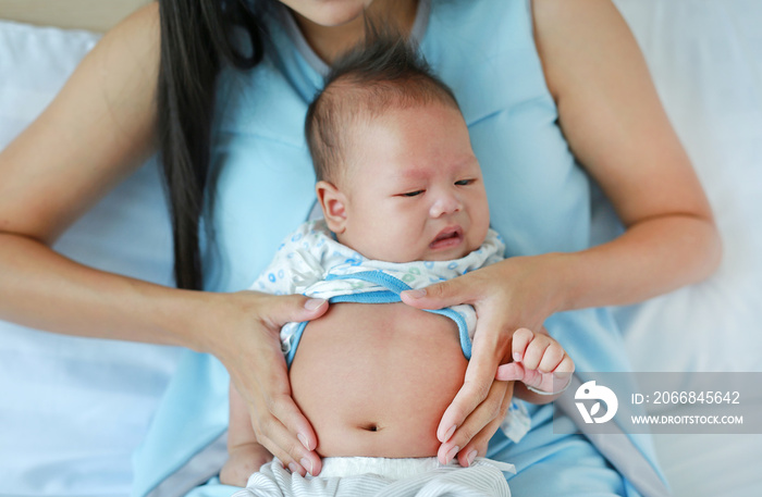 Close-up hands of mother touching and take care infant with pain in her Stomach.