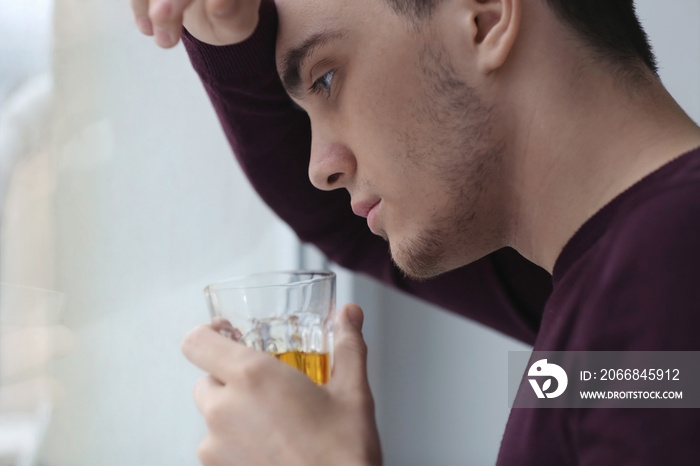 Handsome depressed man with glass of alcohol, closeup