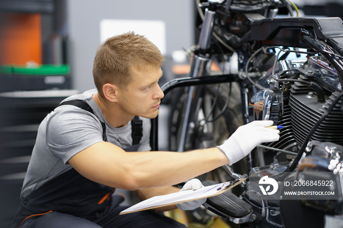 A man in the garage is checking a motorcycle