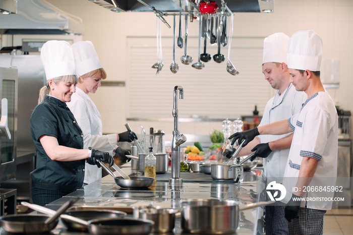 Cooks prepare meals on an electric stove in a professional kitchen in a restaurant or hotel.