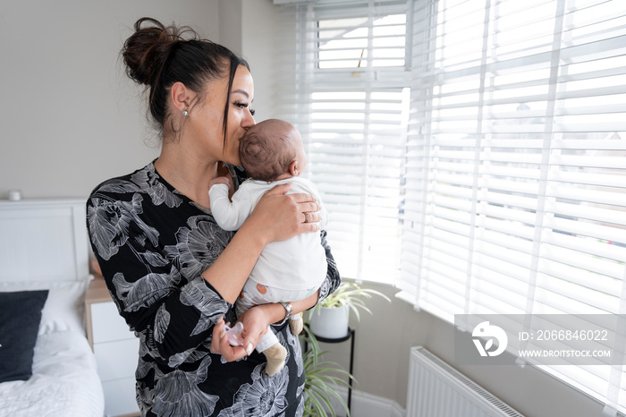 Mother carrying newborn baby girl at home