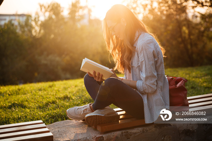 Side view of smiling woman in eyeglasses sitting on bench