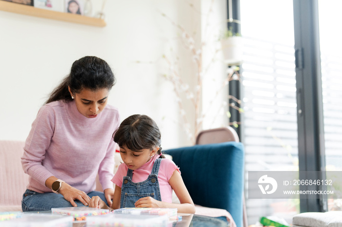 Mother and daughter playing with beads in living room