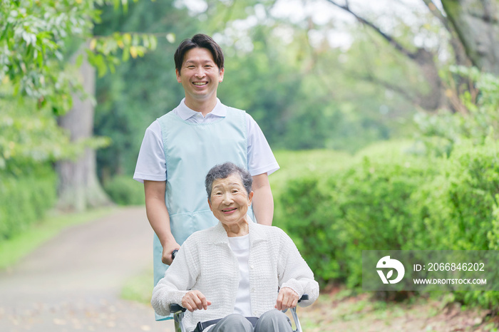 介護士と車椅子に乗った高齢者　屋外