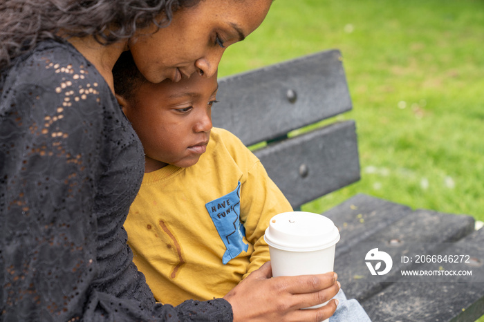 Mother and son sitting on bench in park