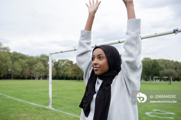 Smiling woman in hijab playing soccer in park