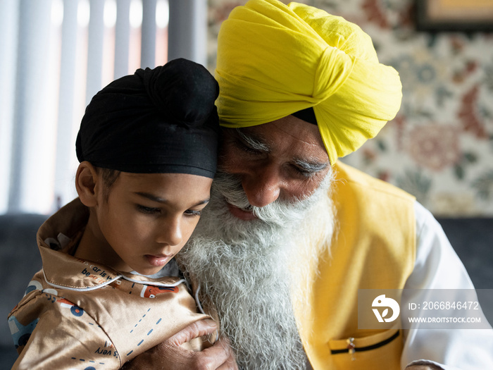 Grandfather and grandson (6-7) in traditional clothing hugging at home